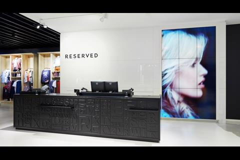 Digital screens behind the checkout showcase the Reserved proposition